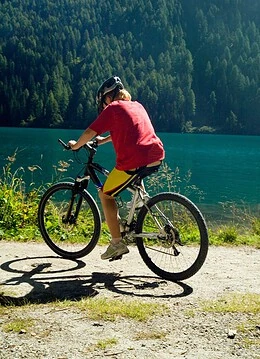 O persoană cu bicicleta pe lângă un lac natural