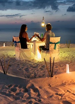 Un cuplu luând cina la lumina felinarului pe plajă