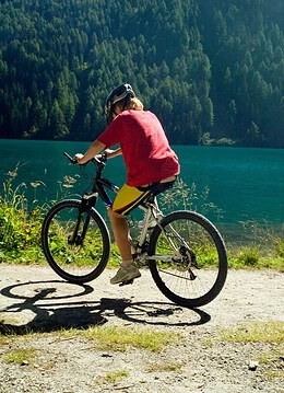 O persoană cu bicicleta pe lângă un lac