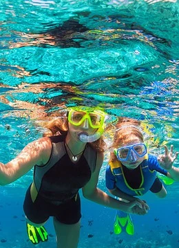 O femeie cu un copil practicând snorkeling