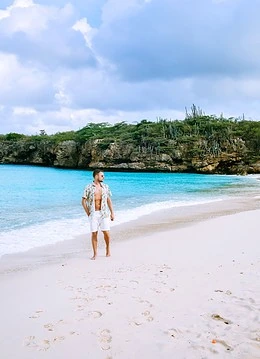 Bărbat pe o plajă cu nisp alb și o apă de culoare turcoaz din Curacao
