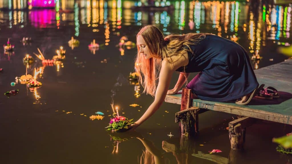 O fată care lansează pe apă o lumânare în festivalul Loi Krathong