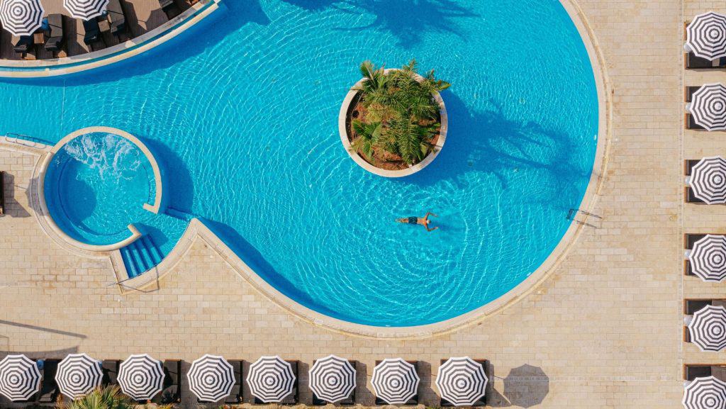 Vedere panoramică asupra unei piscine în formă de cerc cu șezlonguri și umbrele pe lângă