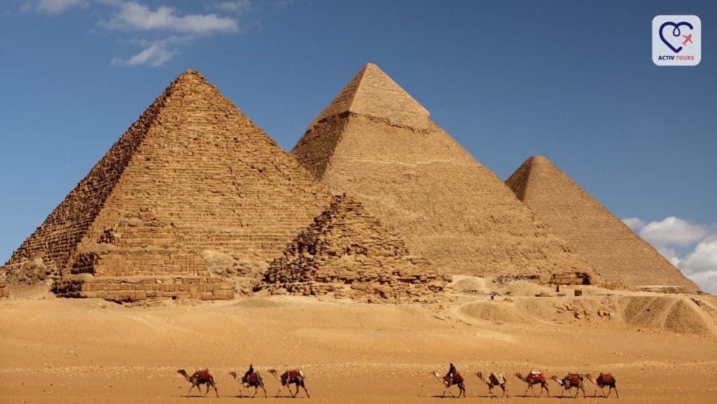 Oameni pe cămile trecând prin fața piramidelor din Giza